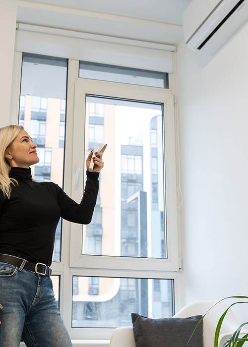 Woman_Turning_On_Air_Conditioner_Best1_Plumbing_and_Heating